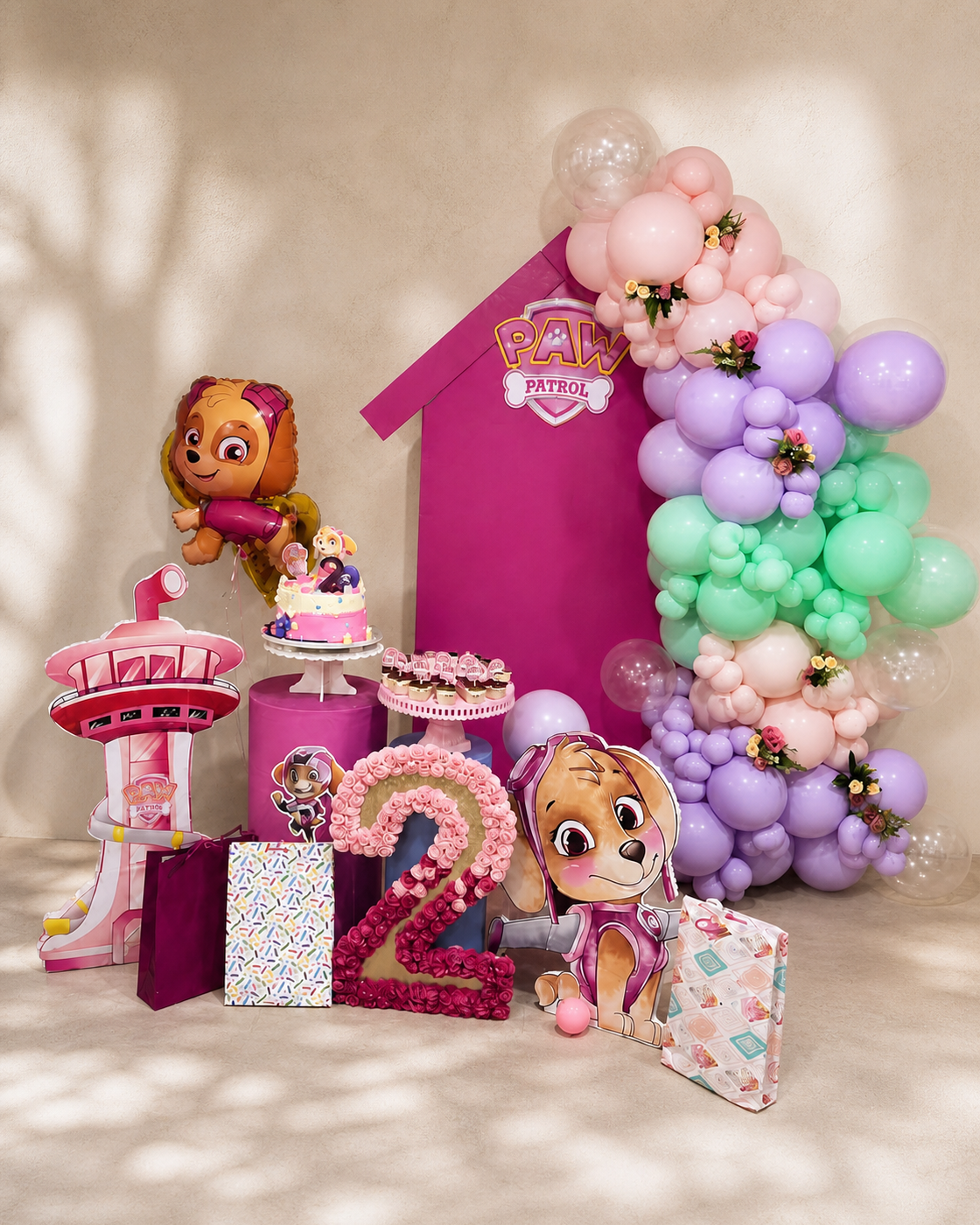 Celebración infantil completa en rosa, lila y verde con mesa de tarta y guirnalda de globos