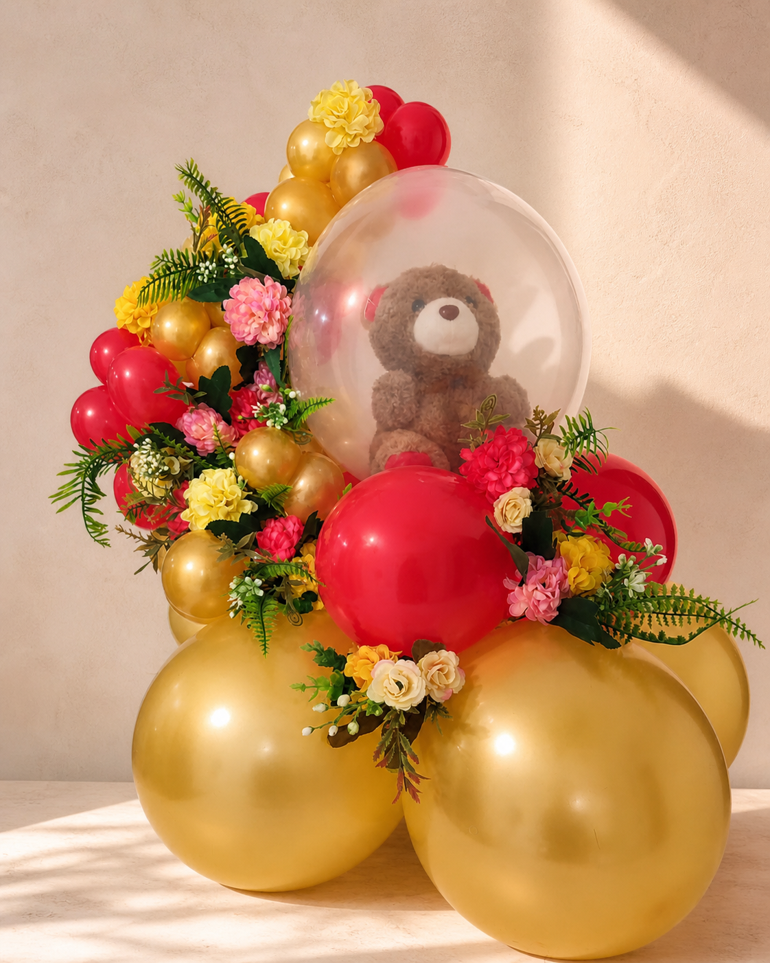 Arreglo de globos y flores frescas con peluche dentro de un globo burbuja dorado