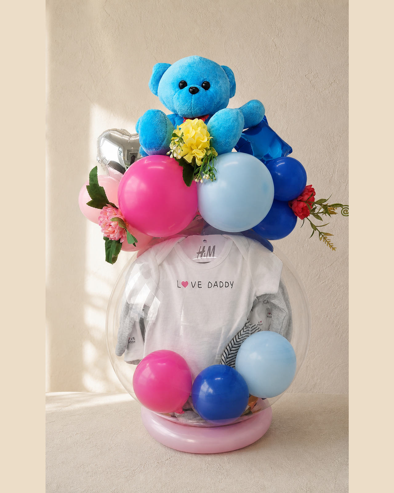 Regalo de nacimiento con globos azules y rosas y peluche dentro de un globo burbuja